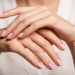 Delicate hands with perfect pink manicured nails rest gracefully.