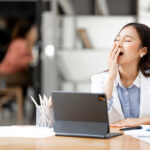 Tired sleepy woman yawning, working at office desk, overwork and sleep deprivation concept
