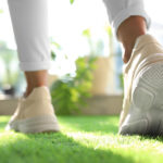 Young woman wearing stylish sneakers on green grass, closeup